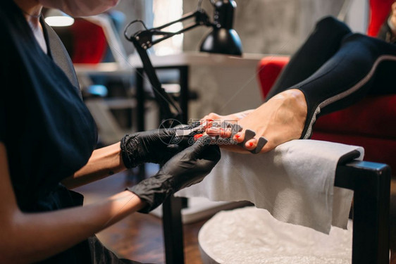 戴黑手套的美容师对顾客做足疗图片