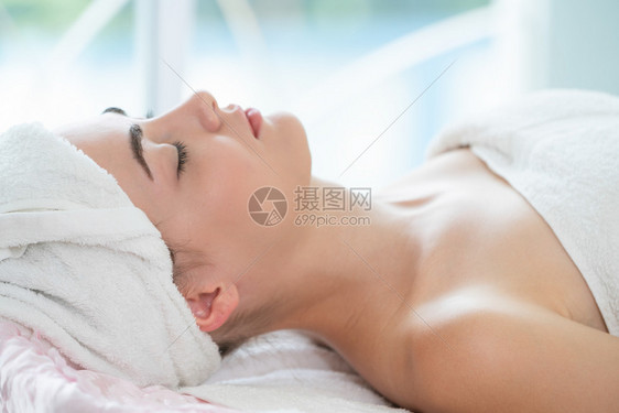 在温泉床接受头部按摩理疗的美女图片