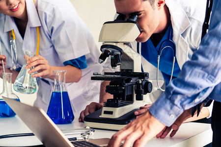 科学家们穿着实验室大衣在审查测试管和科学仪器的生物化样本图片