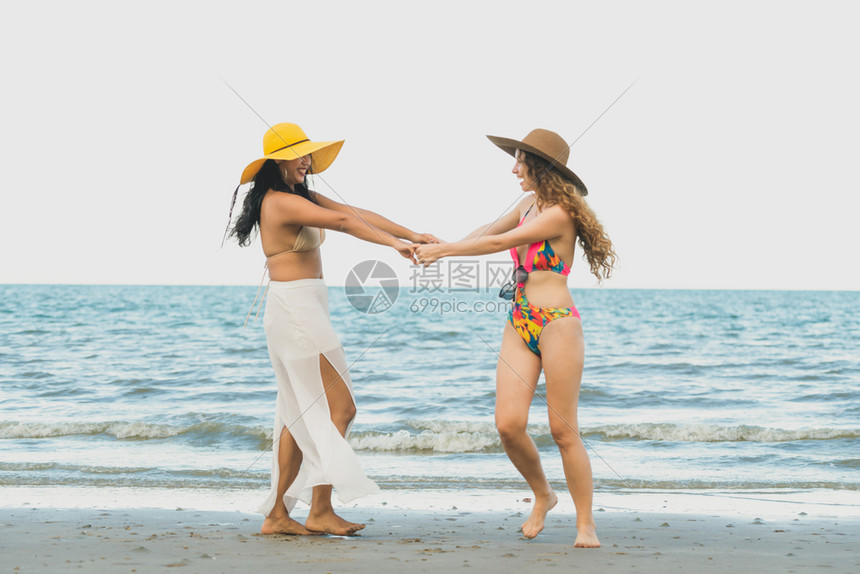 穿着比基尼的快乐妇女一起在夏季假期热带沙滩上跳舞旅行生活方式夏天在沙滩上跳舞的快乐妇女图片