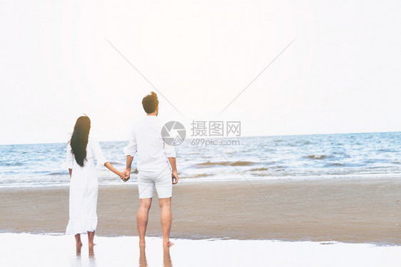 快乐的情侣在沙滩上牵手约会图片