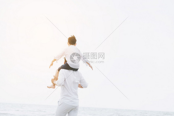 儿子骑在父亲脖子上在沙滩玩图片