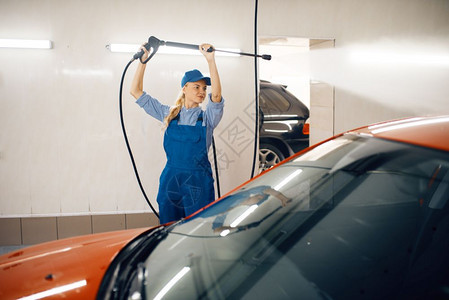 女清洗员身穿制服手持高压水枪清洗汽辆业务图片