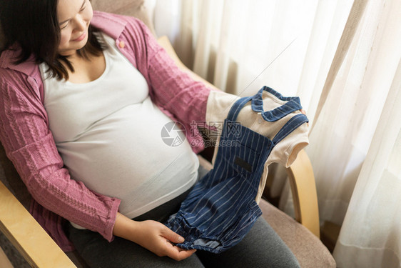 孕妇展示自己给孩子买的婴儿服图片