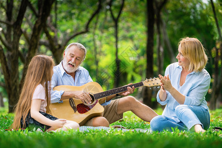 快乐的家庭弹吉他和在公园一起唱歌图片