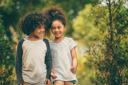 公园里快乐的小男孩小女孩两个一起在花园里散步背景图片