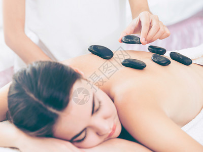 女顾客在温泉美容院接受按摩师的热石按摩治疗图片