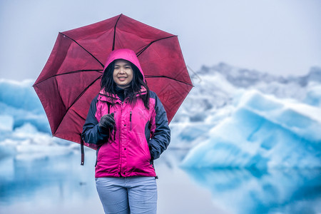 女游客撑伞站在冰川中拍照图片