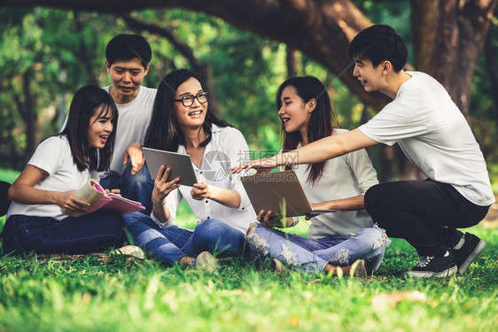 大学生们坐在草地上使用电脑学习图片