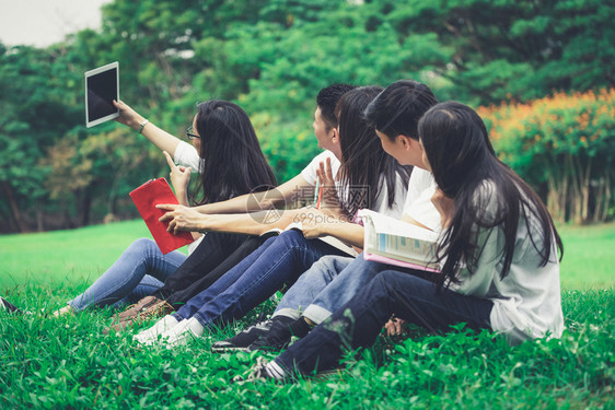 大学生们坐在草地上拍集体照图片