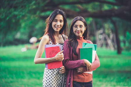 女学生抱着书籍站在公园里图片