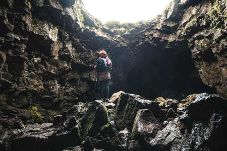 女旅行者探索冰原的熔岩隧道图片