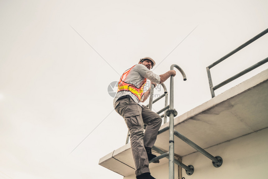 青年建筑工程师攀登楼顶的梯子做工程项目图片