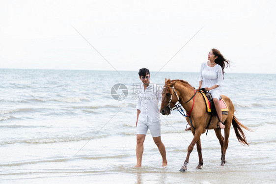 夫妇在热带海滩骑马图片