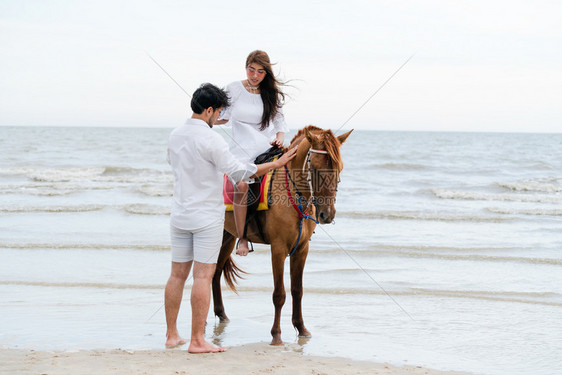 夫妇在热带海滩骑马图片