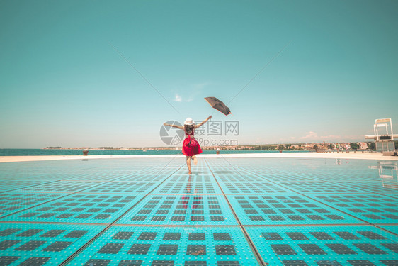 女旅行者在户外迪斯科地板上撑伞跳舞图片