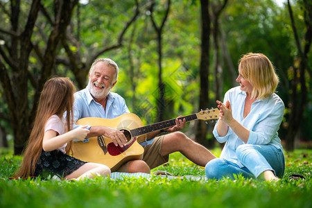 快乐的家庭夏天坐在公园里一起唱歌弹吉他图片