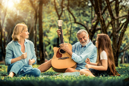 快乐的家庭夏天坐在公园里一起唱歌弹吉他图片