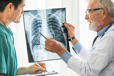 高级男医生与另一名医生一起检查病人胸部受伤的x光片图片
