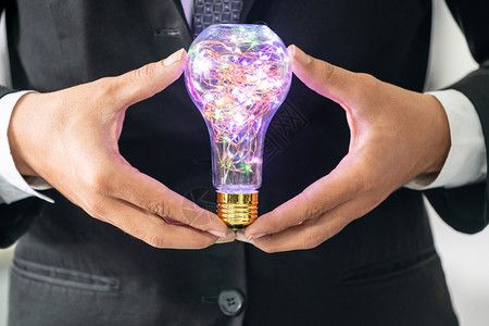 商人手里握着灯泡商业创造力和想法的概念图片