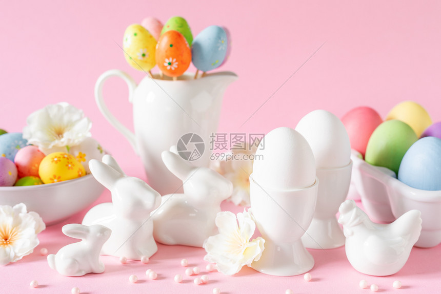 粉红色背景的鸡蛋和兔子装饰品图片