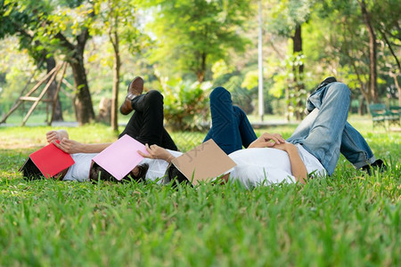 男女青年用书本盖住脸在草地上睡觉图片