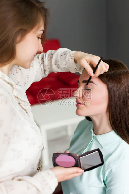 女化妆师手拿画笔在女孩脸上化妆图片