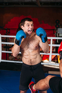 拳击手在场上脸色愤怒的肌肉拳击手训练健身房的背景拳击运动图片