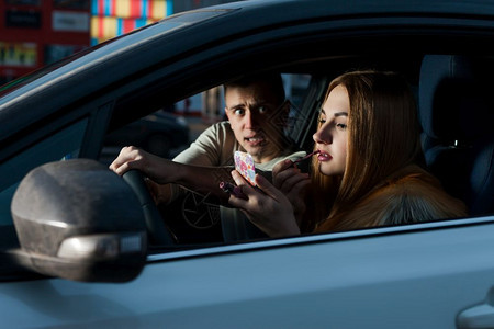 男人驾驶汽车而年轻女人化妆危险驾驶图片