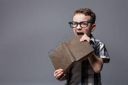 小男孩在咬一本书图片