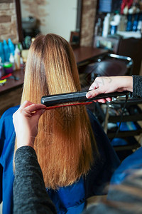 理发师正在用烫发器给金色女生做发型图片素材