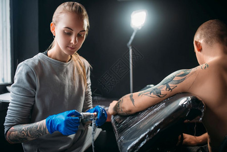 女纹身师用机器在肩膀上纹身图片