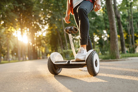 在夏季公园的旋律板上骑着男青年的子用电旋律板进行户外娱乐使用平衡技术进行生态运输背景图片