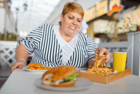 严重超重的女人在餐厅吃薯条图片