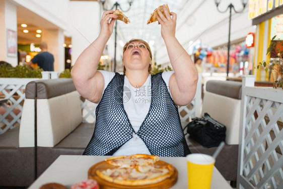 肥胖症超重的女人吃披萨图片