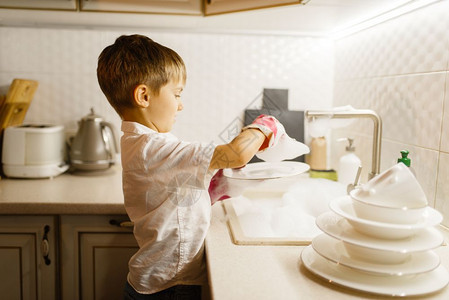小男孩在厨房用手套洗碗图片