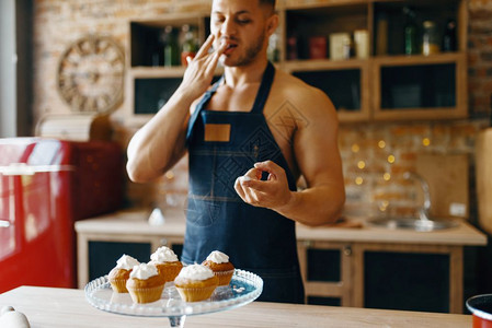 裸体男子在厨房做甜点,上加奶油。 裸体男性子在家做早餐,不穿衣服做饭。图片