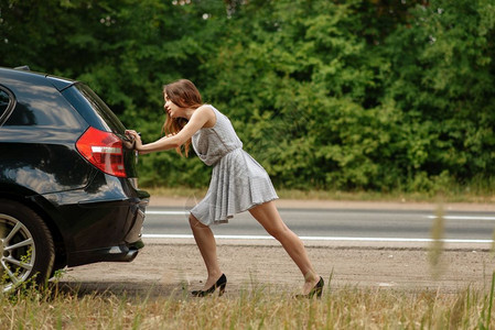 妇女在公路上推发生故障的车辆图片