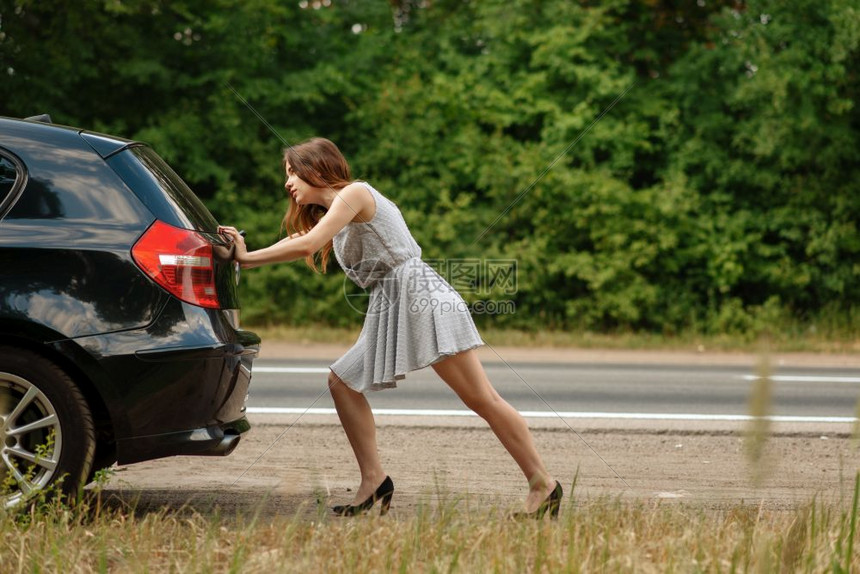 妇女在公路上推发生故障的车辆图片