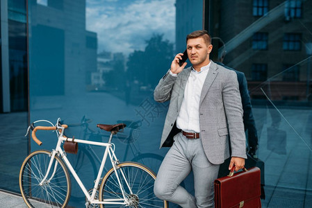 商人在市区的自行车上通过手机交谈图片