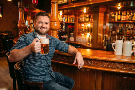 在酒吧的柜台喝着啤酒杯的开心男人喝着酒的有胡子男在酒吧玩得开心图片