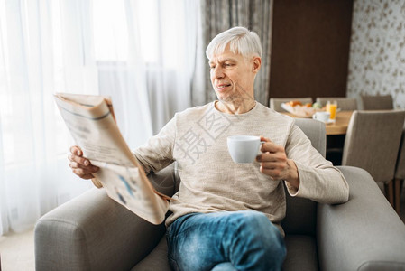 拿着咖啡杯的男人正在看报纸图片