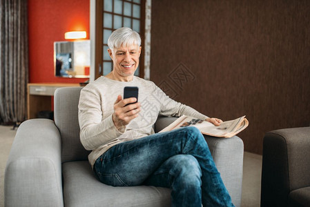 穿牛仔裤的成年男子在沙发上玩手机图片