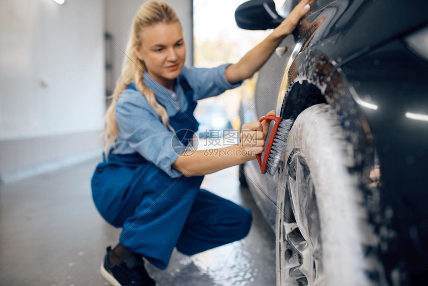 身穿制服的女人正在拿刷子清洗车上的泡沫图片