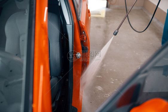 身穿制服的妇女用高压水枪清洁车辆车门图片