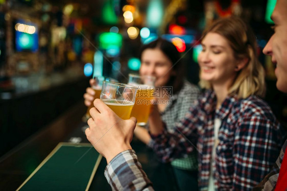 足球迷在体育酒吧的柜台喝轻啤酒电视广播年轻朋友庆祝最喜爱球队的胜利图片