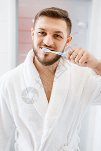 穿浴袍的男人在浴室里刷牙图片