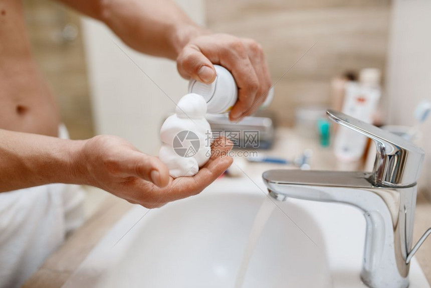 男子在洗手间向手中挤出剃须泡沫图片