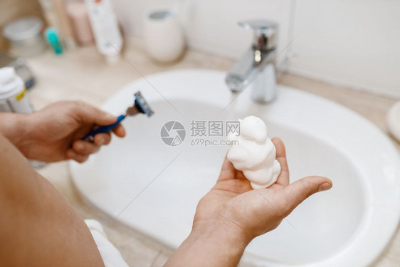 男子在洗手间向手中挤出剃须泡沫图片