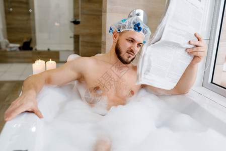 男人在洗泡泡澡时阅读报纸图片